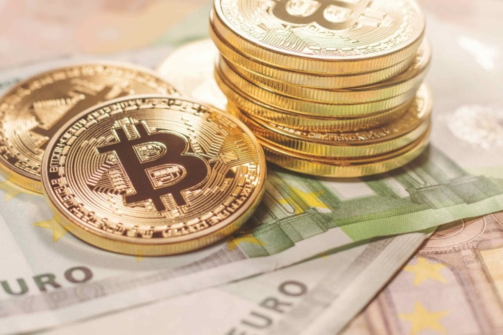 Gold coins with Bitcoin logo stacked on Euro bills